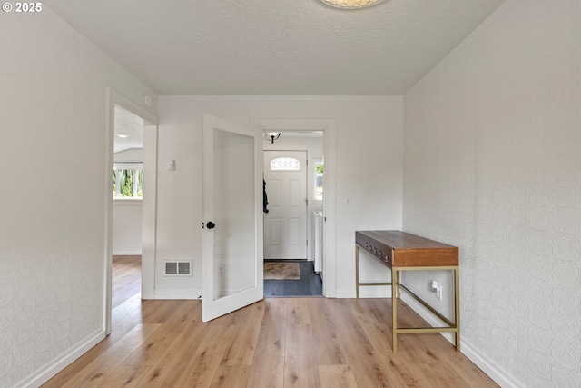 entrance foyer featuring baseboards, light wood-style flooring, and a textured ceiling