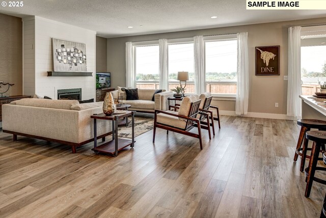 1124 N Helens View Dr, Ridgefield, WA 98642 - living room with a large fireplace, baseboards, a textured ceiling, light wood-type flooring, and recessed lighting