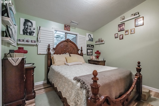 bedroom featuring a textured ceiling, hardwood / wood-style flooring, and vaulted ceiling