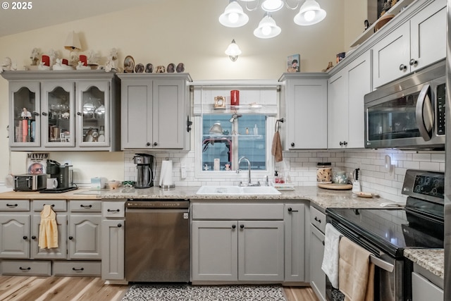 kitchen with gray cabinets, sink, light stone countertops, and stainless steel appliances