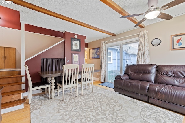 living room with ceiling fan, light hardwood / wood-style flooring, beamed ceiling, and a textured ceiling