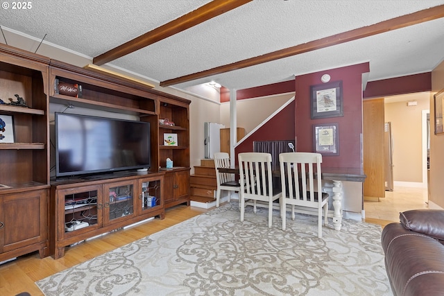 living room with a textured ceiling, beamed ceiling, and light wood-type flooring