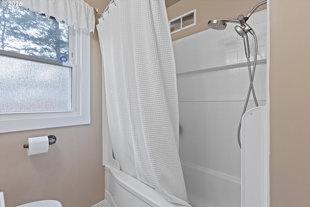 bathroom with plenty of natural light, toilet, and shower / bath combo with shower curtain