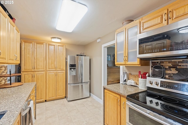 kitchen featuring light stone counters, appliances with stainless steel finishes, decorative backsplash, and light brown cabinets