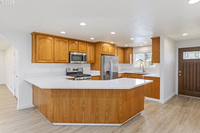 6253 SW 204th Pl, Beaverton, OR 97078 - kitchen featuring stainless steel appliances, brown cabinets, a peninsula, light countertops, and light wood-type flooring