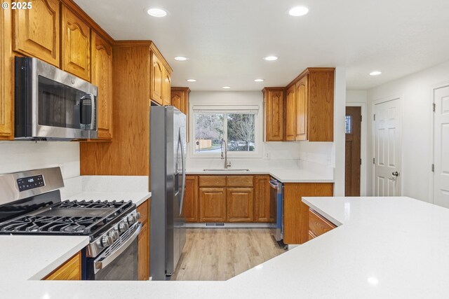 6253 SW 204th Pl, Beaverton, OR 97078 - kitchen featuring appliances with stainless steel finishes, light wood finished floors, brown cabinetry, recessed lighting, and light countertops
