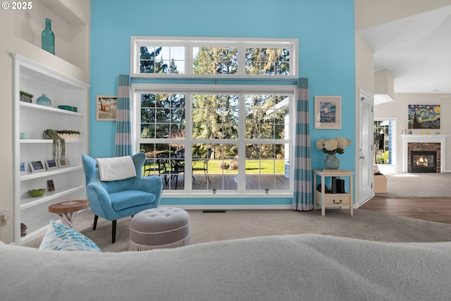 sitting room featuring carpet floors, built in features, a healthy amount of sunlight, and a high ceiling