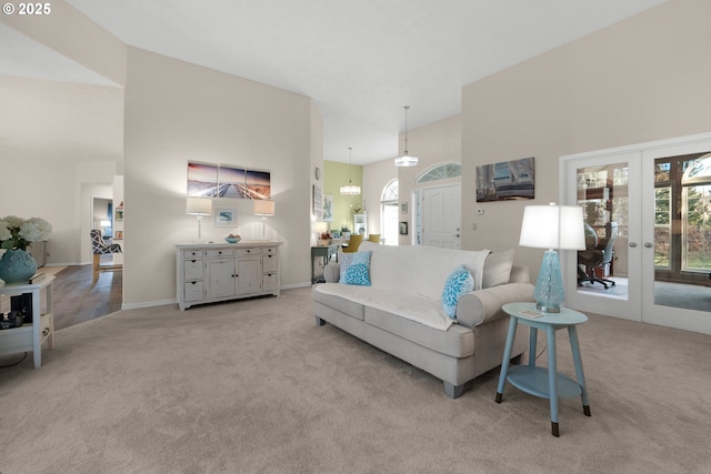 living room featuring light carpet, a towering ceiling, and french doors