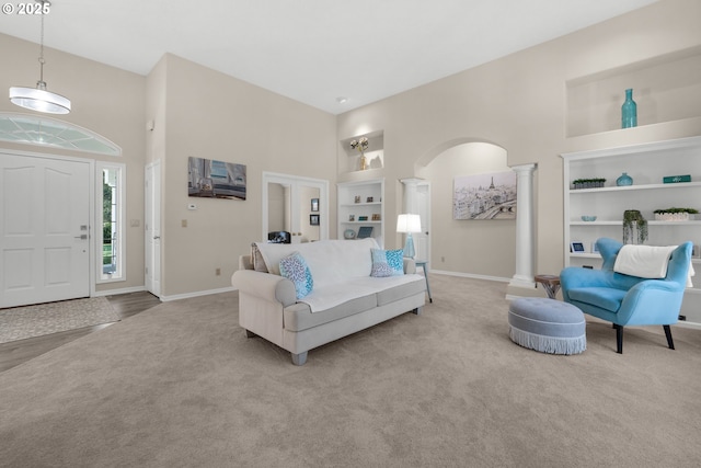 living room featuring light colored carpet, decorative columns, built in features, and a high ceiling