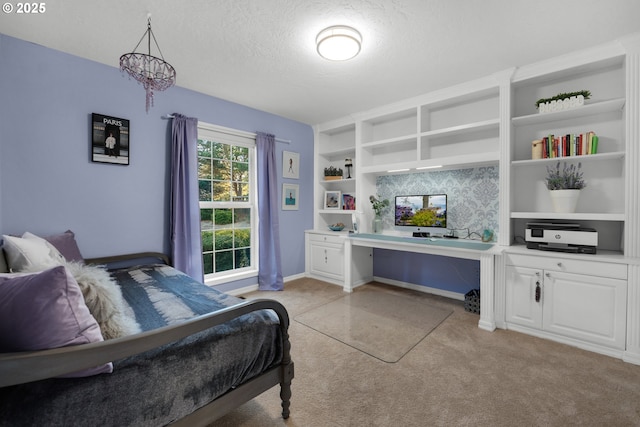 bedroom featuring light carpet, built in desk, and a textured ceiling