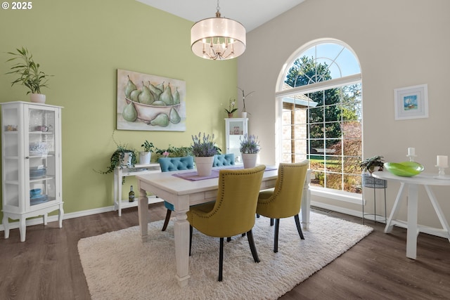 dining area with dark wood-type flooring and an inviting chandelier