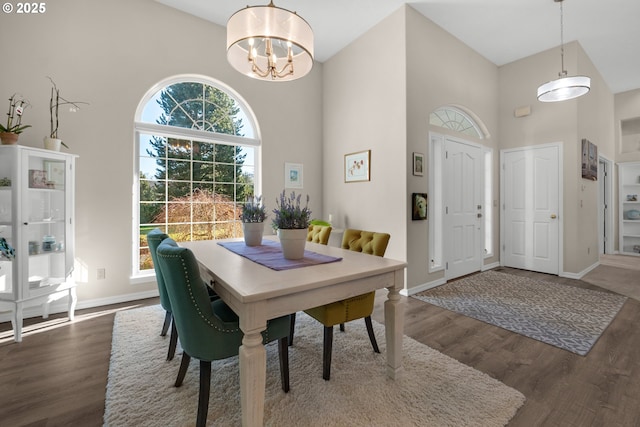 dining space featuring an inviting chandelier, dark hardwood / wood-style floors, and a high ceiling