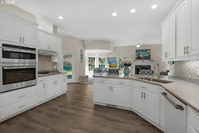 kitchen with appliances with stainless steel finishes, sink, white cabinets, dark hardwood / wood-style flooring, and kitchen peninsula