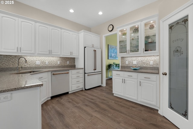 kitchen featuring sink, white appliances, dark wood-type flooring, white cabinets, and dark stone counters