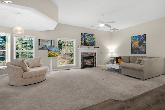 living room featuring ceiling fan, a healthy amount of sunlight, a high end fireplace, and carpet