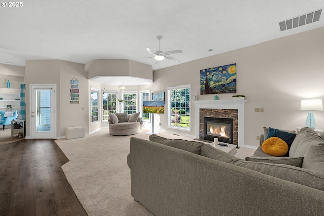 living room with hardwood / wood-style flooring, ceiling fan, a fireplace, and a textured ceiling