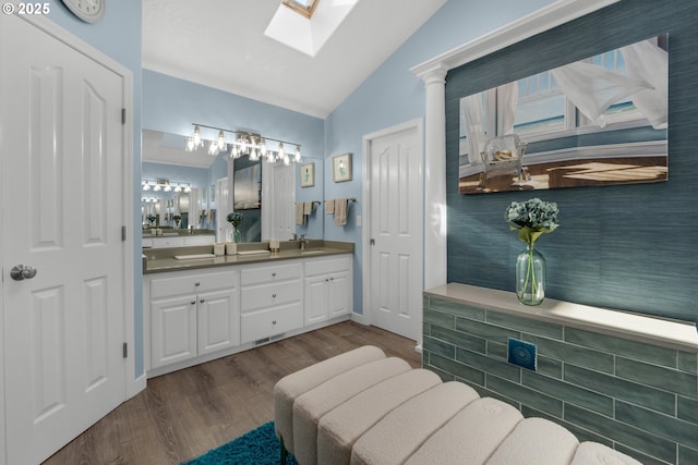 bathroom with vanity, wood-type flooring, and vaulted ceiling with skylight