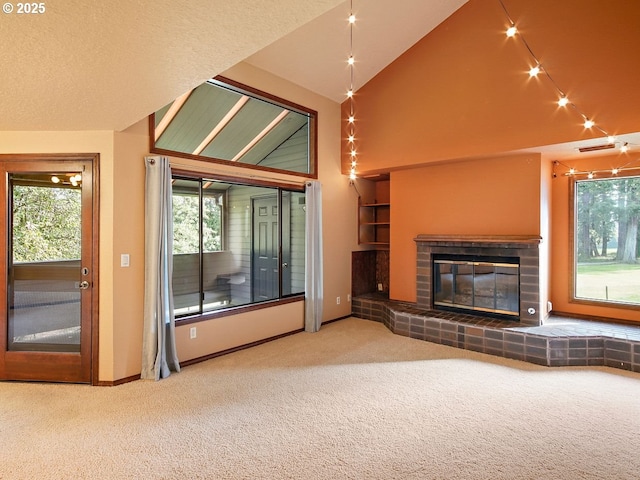 unfurnished living room featuring a fireplace, high vaulted ceiling, plenty of natural light, and carpet