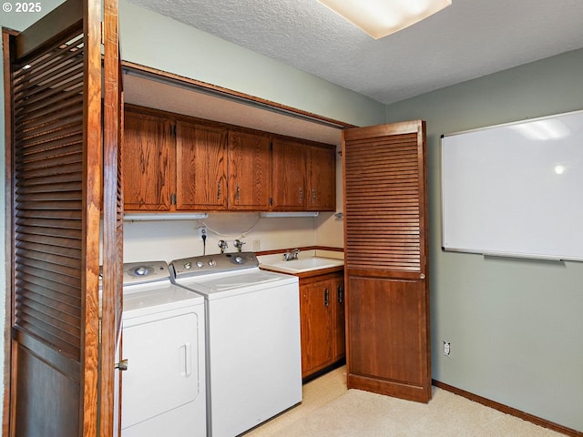 clothes washing area featuring washer and dryer, sink, cabinets, and a textured ceiling