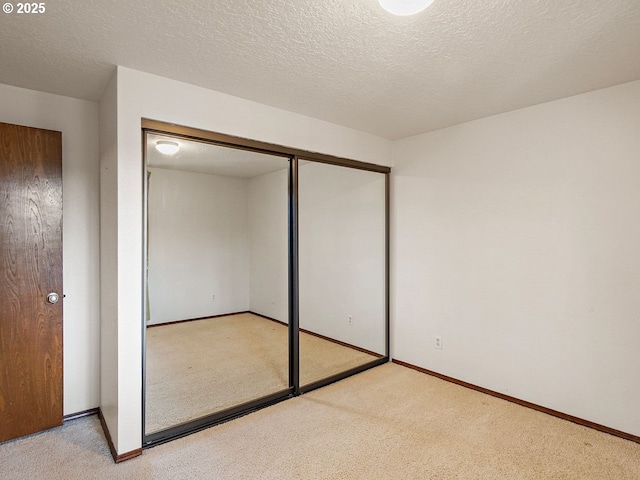 unfurnished bedroom with light carpet, a closet, and a textured ceiling