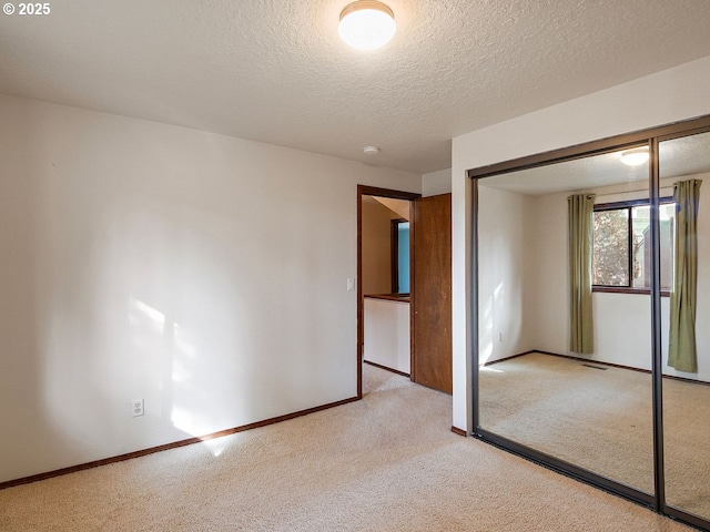 unfurnished bedroom featuring light carpet, a closet, and a textured ceiling