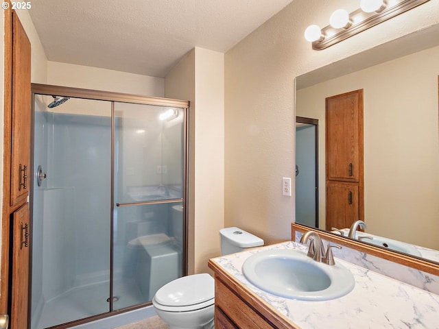 bathroom featuring vanity, a textured ceiling, a shower with shower door, and toilet