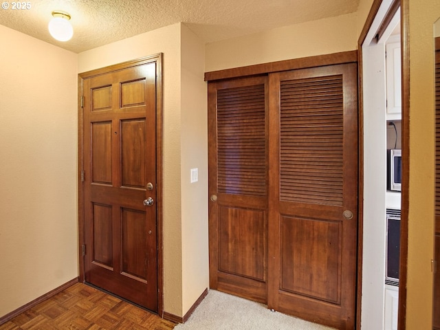 entryway featuring parquet flooring and a textured ceiling