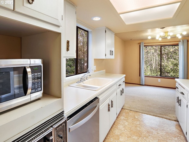 kitchen featuring plenty of natural light, sink, stainless steel dishwasher, and white cabinets