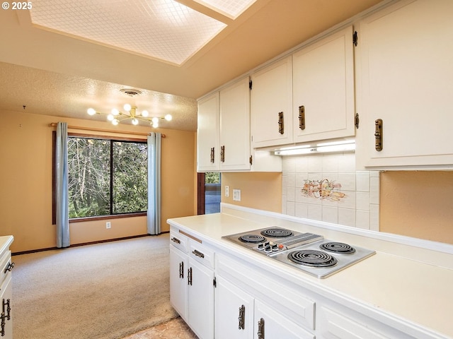 kitchen with white cabinetry, backsplash, white electric cooktop, and light carpet