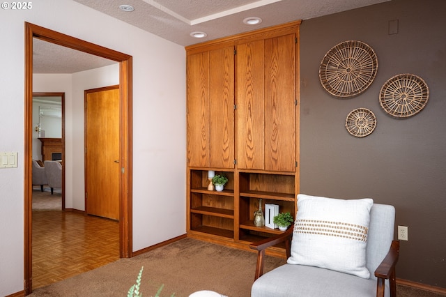 sitting room with a textured ceiling, baseboards, and a fireplace