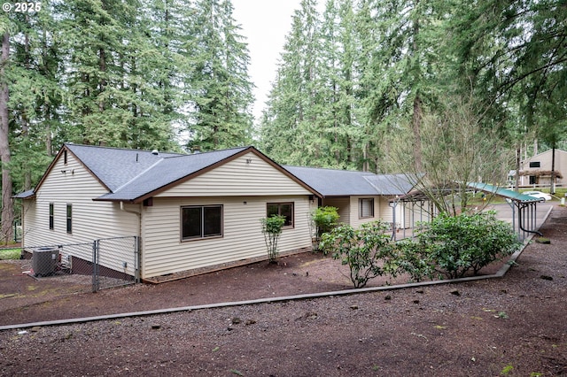 back of house featuring fence, central AC unit, and a shingled roof