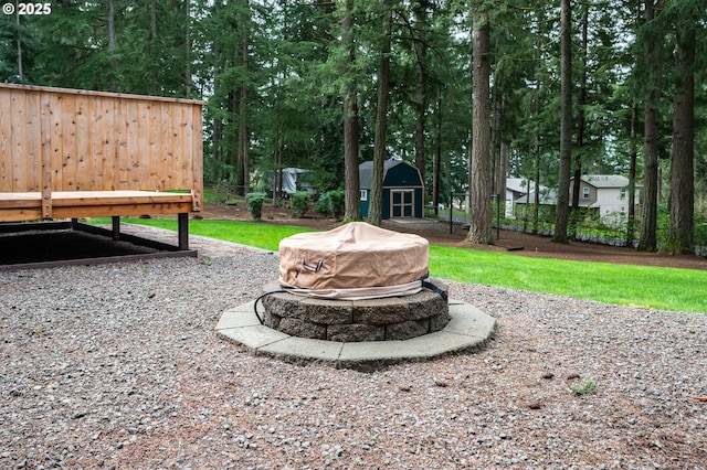view of yard featuring a storage unit, an outdoor structure, and an outdoor fire pit