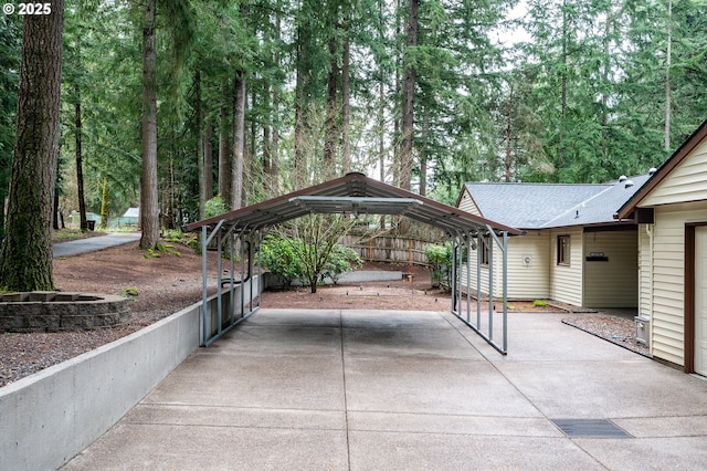 view of parking / parking lot featuring fence, a carport, and concrete driveway