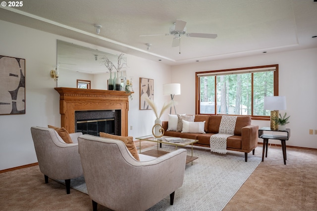 carpeted living area with a glass covered fireplace, baseboards, a ceiling fan, and a tray ceiling