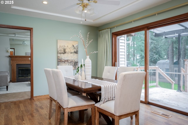 dining room with a raised ceiling, a ceiling fan, wood finished floors, and visible vents