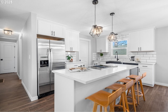 kitchen with a center island, dark wood finished floors, decorative backsplash, appliances with stainless steel finishes, and white cabinets