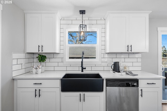 kitchen featuring a sink, white cabinetry, light countertops, dishwasher, and tasteful backsplash