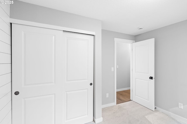 unfurnished bedroom with carpet floors, a closet, and baseboards