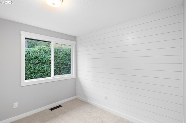 carpeted spare room featuring visible vents, a textured ceiling, and baseboards