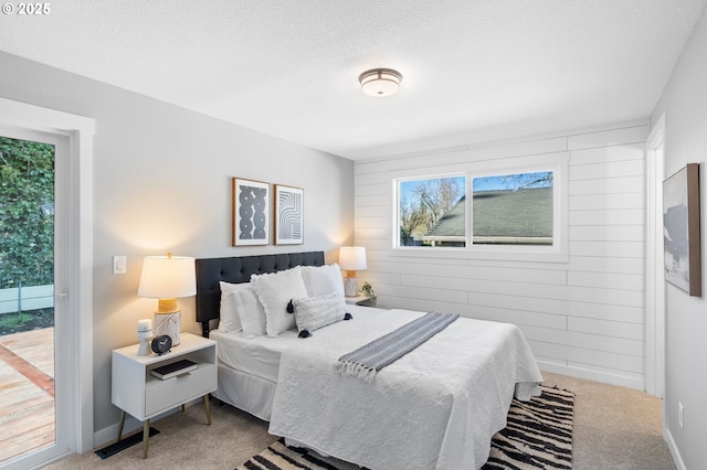 carpeted bedroom featuring wood walls, access to outside, baseboards, and a textured ceiling