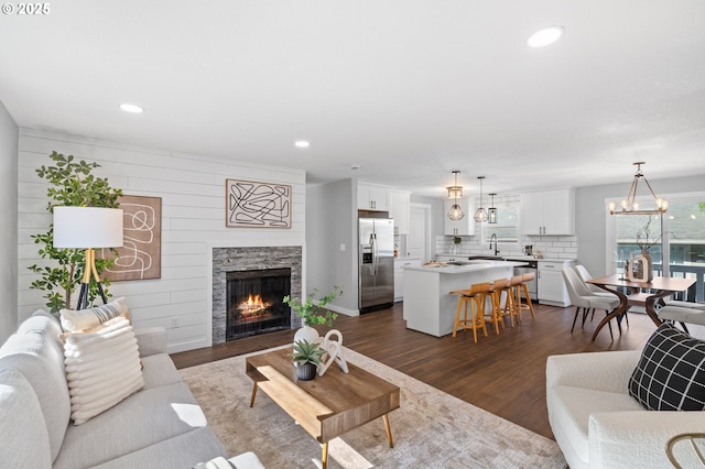 living room featuring recessed lighting, dark wood finished floors, and a stone fireplace