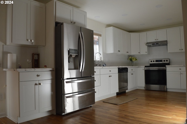 kitchen featuring under cabinet range hood, stainless steel appliances, wood finished floors, white cabinetry, and light countertops