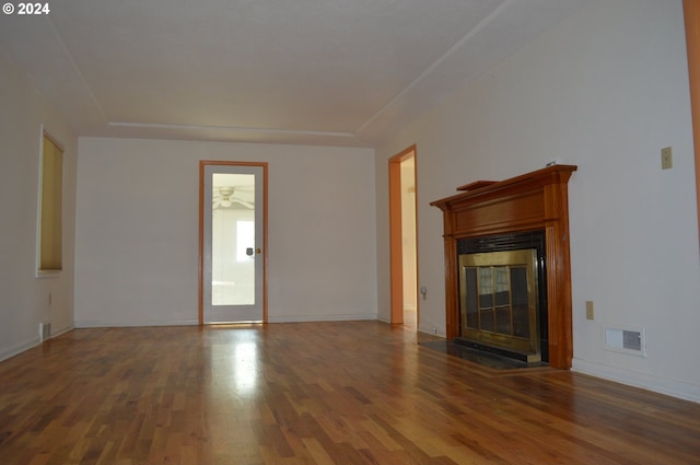 unfurnished living room featuring baseboards, a fireplace with flush hearth, visible vents, and wood finished floors