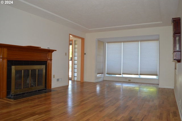 unfurnished living room featuring a fireplace with flush hearth, baseboards, and wood finished floors