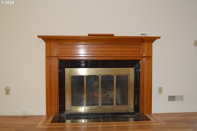 room details with a fireplace with flush hearth, visible vents, baseboards, and wood finished floors