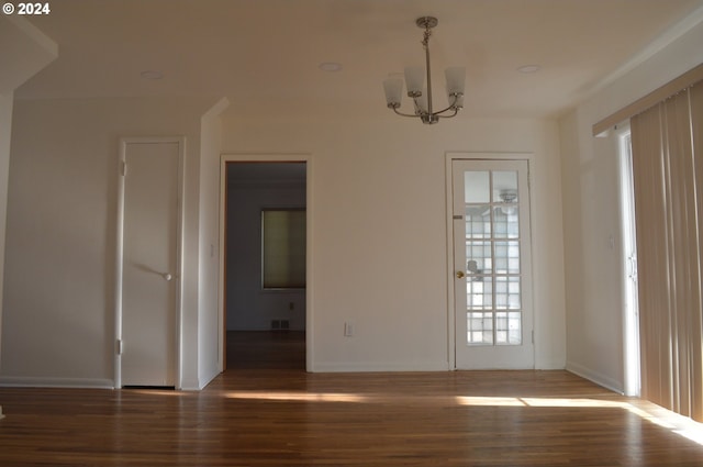 unfurnished dining area featuring a chandelier, wood finished floors, visible vents, and baseboards