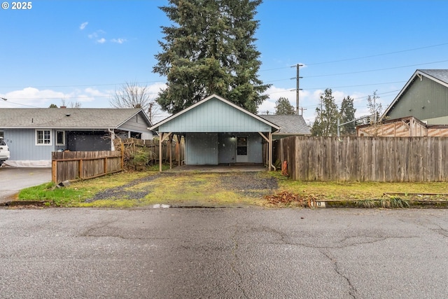 view of front of property featuring a detached carport, driveway, and fence