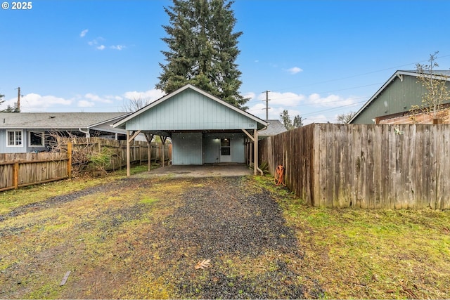 rear view of house with a carport, driveway, and a fenced backyard