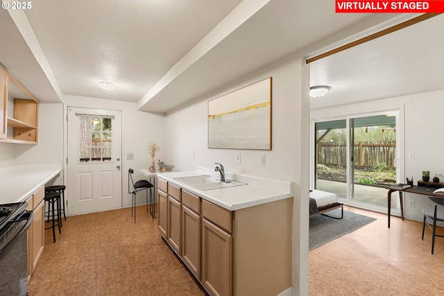 kitchen with stove, light countertops, light floors, and a sink