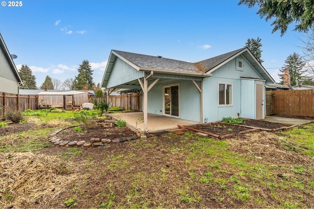 back of property with a patio area, a fenced backyard, and roof with shingles